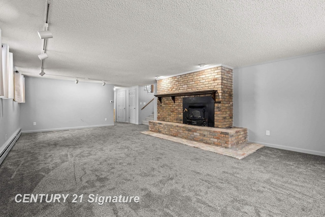 unfurnished living room featuring carpet flooring, a textured ceiling, rail lighting, and a wood stove