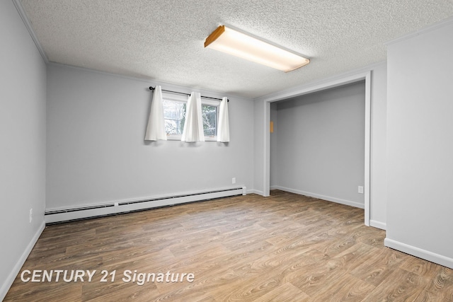 spare room with a baseboard radiator, a textured ceiling, and light hardwood / wood-style floors