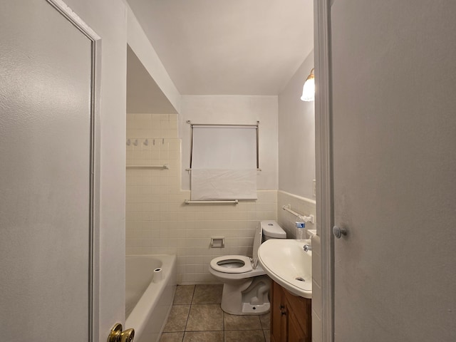 bathroom featuring vanity, tile walls, tile patterned flooring, toilet, and a bathing tub