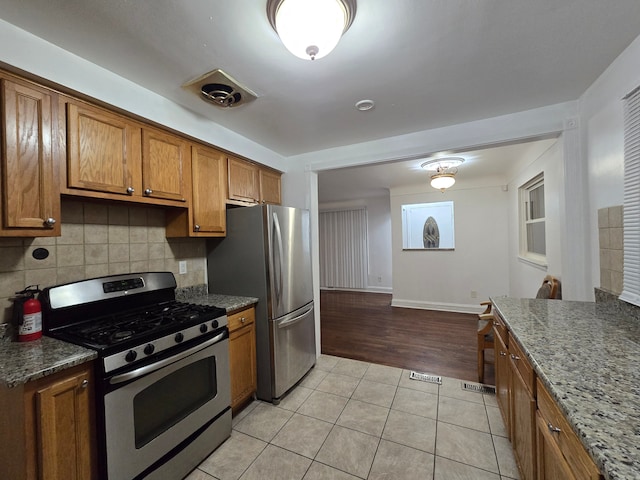 kitchen with decorative backsplash, light tile patterned floors, and appliances with stainless steel finishes