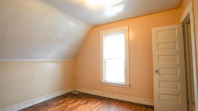 additional living space with hardwood / wood-style floors and vaulted ceiling