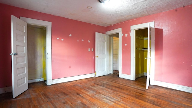 unfurnished bedroom with a textured ceiling and dark hardwood / wood-style flooring