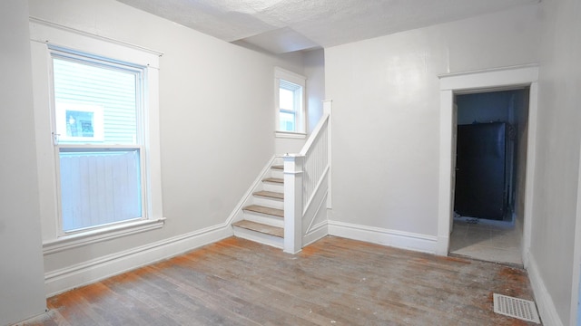 staircase with hardwood / wood-style floors and a textured ceiling