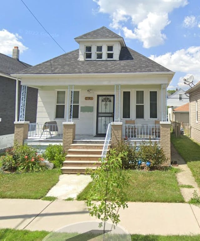 bungalow-style house with a front lawn and covered porch