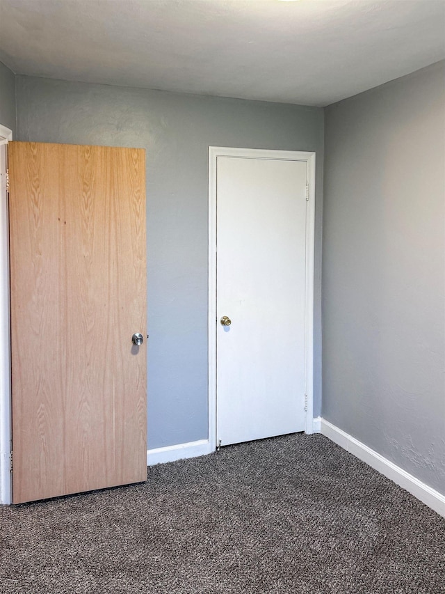 unfurnished bedroom with dark carpet