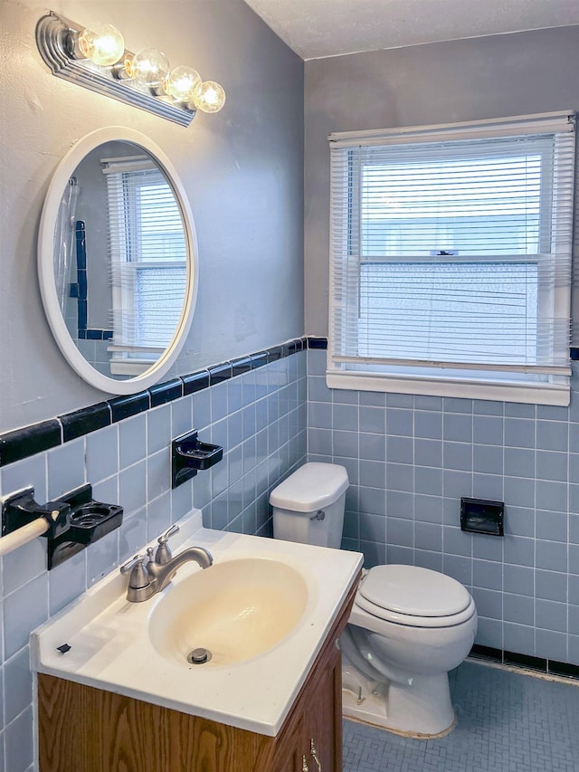 bathroom with tile patterned floors, vanity, a healthy amount of sunlight, and tile walls