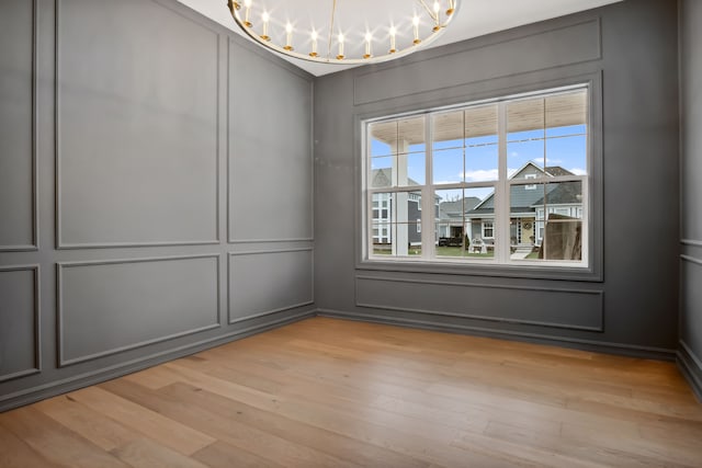 unfurnished room with an inviting chandelier and light hardwood / wood-style floors