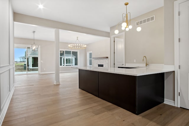 kitchen with sink, hanging light fixtures, kitchen peninsula, and a chandelier