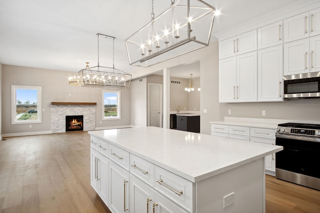 kitchen featuring a center island, light wood-type flooring, appliances with stainless steel finishes, pendant lighting, and white cabinets