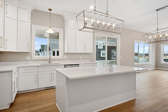 kitchen featuring white cabinetry, a kitchen island, sink, and light wood-type flooring