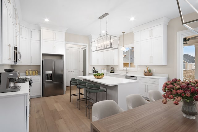 kitchen featuring white cabinetry, a kitchen island, a breakfast bar, and appliances with stainless steel finishes