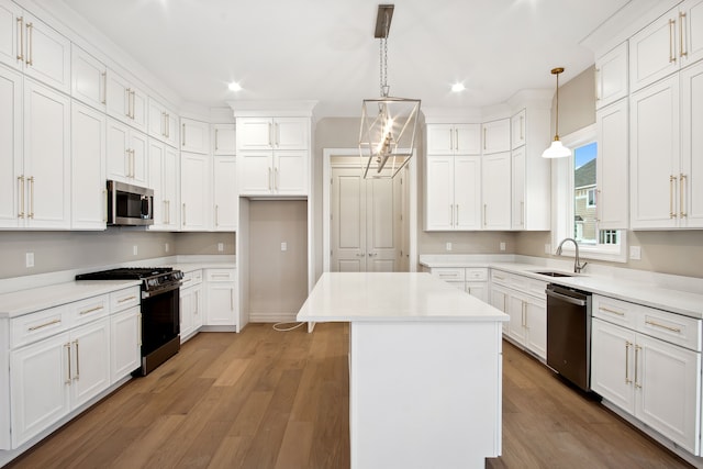 kitchen with pendant lighting, stainless steel appliances, a center island, and white cabinets