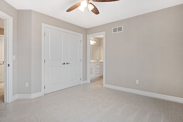 unfurnished bedroom featuring light carpet, connected bathroom, a closet, and ceiling fan