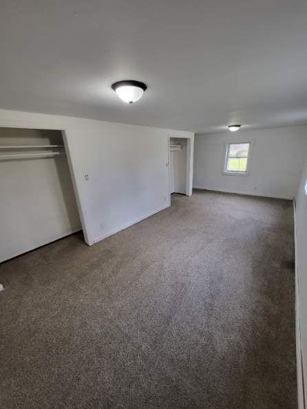 unfurnished bedroom featuring a closet and dark colored carpet