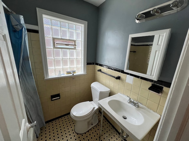 bathroom with tile patterned floors, toilet, tile walls, and sink