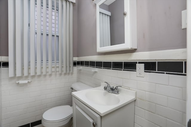 bathroom featuring vanity, toilet, and tile walls