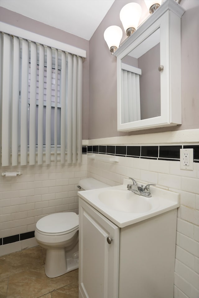 bathroom with vanity, toilet, and tile walls