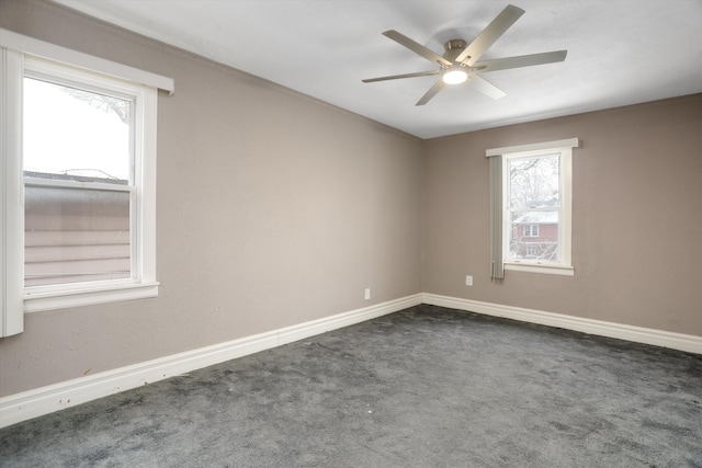 empty room with dark colored carpet, ceiling fan, and a healthy amount of sunlight