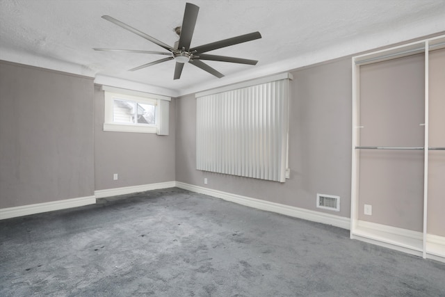 spare room with ceiling fan, dark carpet, and a textured ceiling