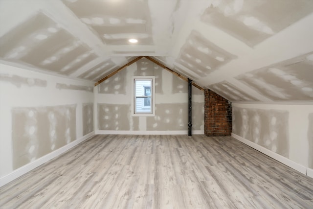 additional living space with vaulted ceiling and hardwood / wood-style flooring