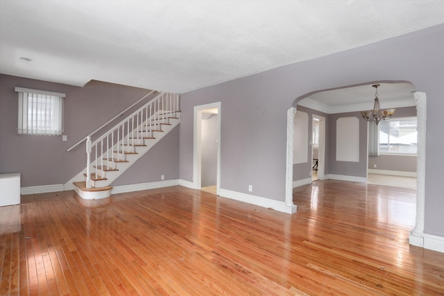 unfurnished living room featuring a chandelier and hardwood / wood-style floors