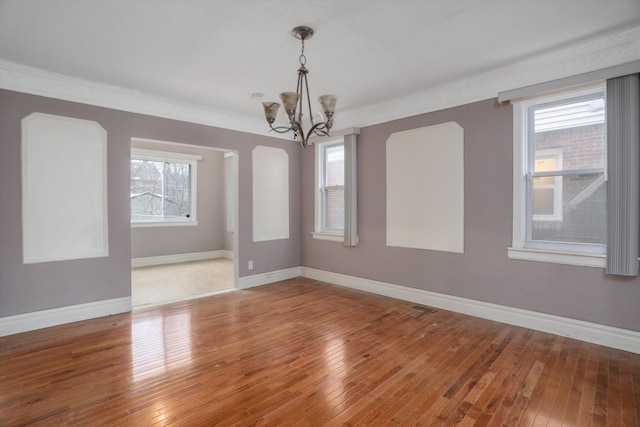 unfurnished room featuring hardwood / wood-style flooring, crown molding, and a chandelier