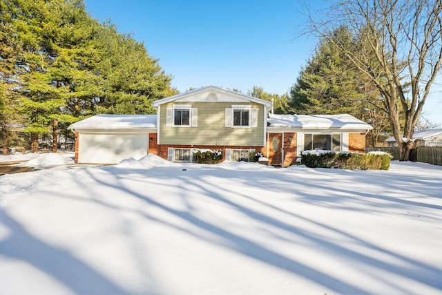 tri-level home featuring concrete driveway, brick siding, and fence