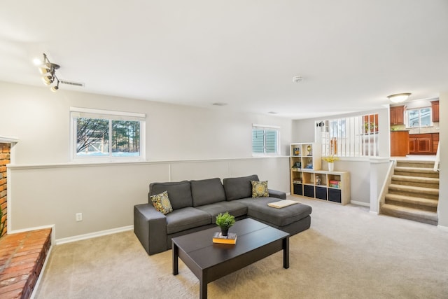 living area with stairs, baseboards, visible vents, and light colored carpet