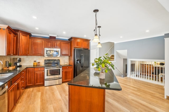 kitchen with stainless steel appliances, a sink, hanging light fixtures, a center island, and tasteful backsplash