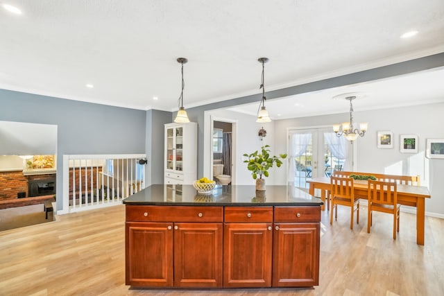 kitchen with hanging light fixtures, dark countertops, light wood-style floors, and french doors