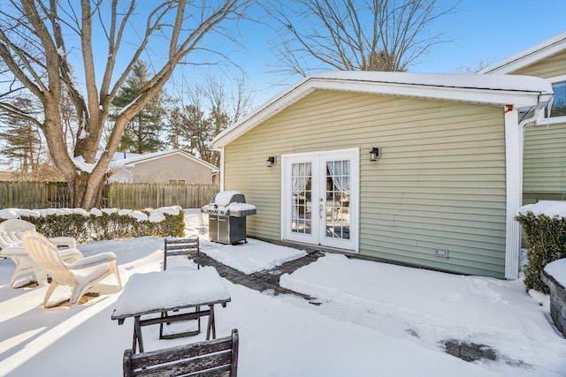 snow covered patio with fence, area for grilling, and french doors