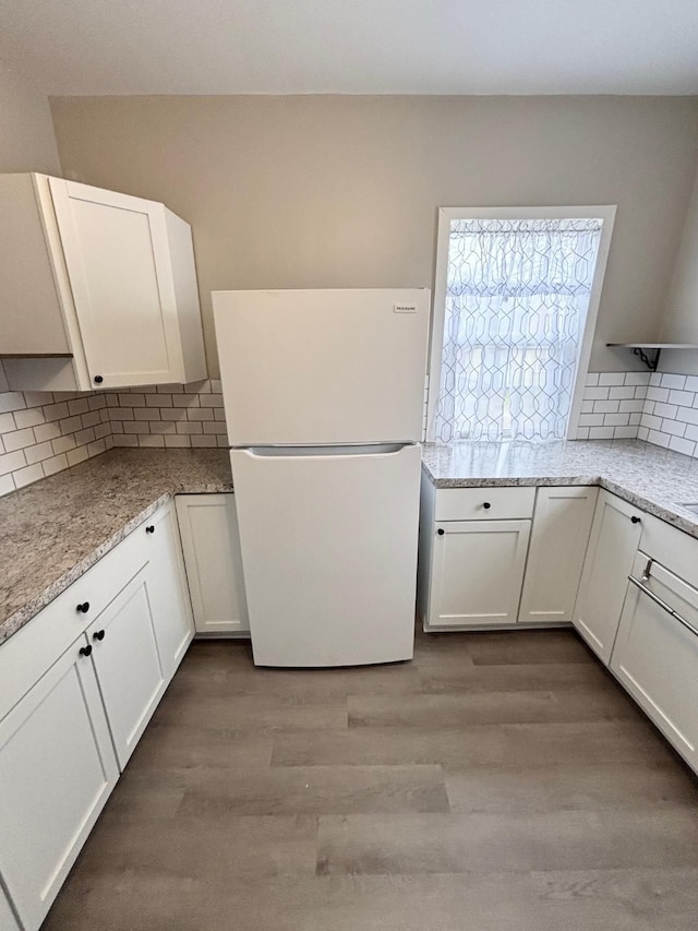 kitchen with white refrigerator, light stone countertops, and white cabinets