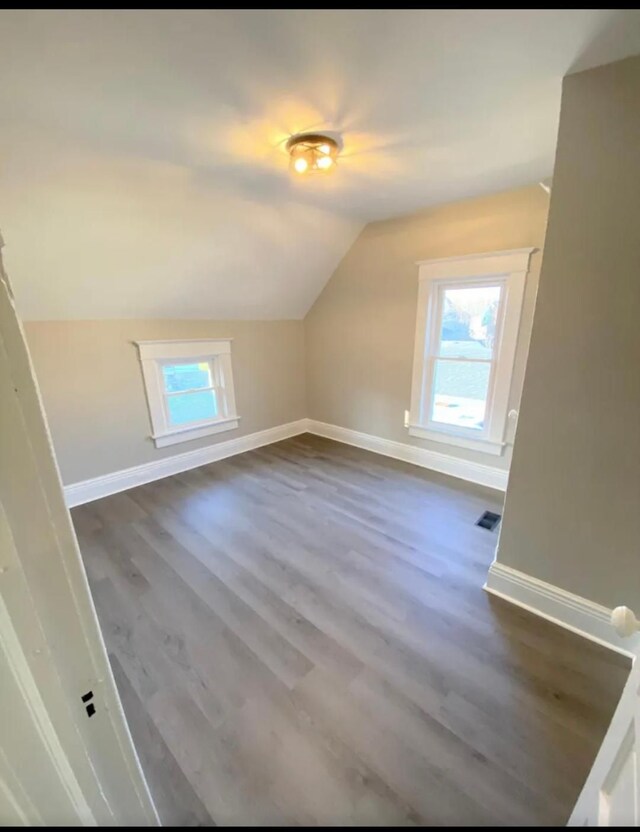 bonus room with vaulted ceiling and dark hardwood / wood-style floors