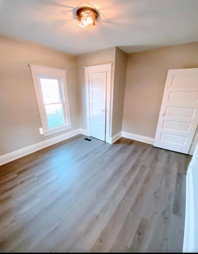 interior space with a closet, wood finished floors, visible vents, and baseboards