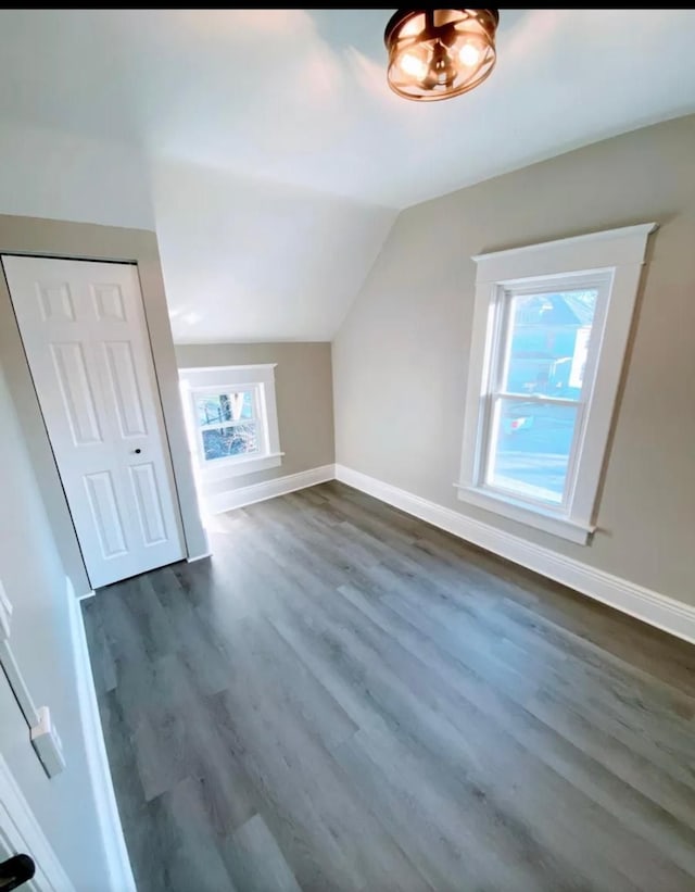 bonus room featuring lofted ceiling, dark wood-style floors, and baseboards