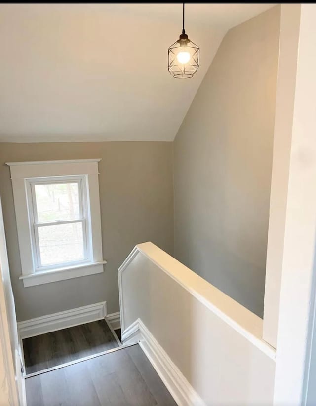 staircase with wood-type flooring and vaulted ceiling