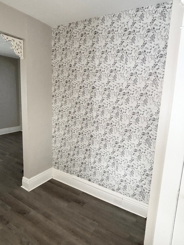 empty room featuring dark wood-type flooring, baseboards, and wallpapered walls