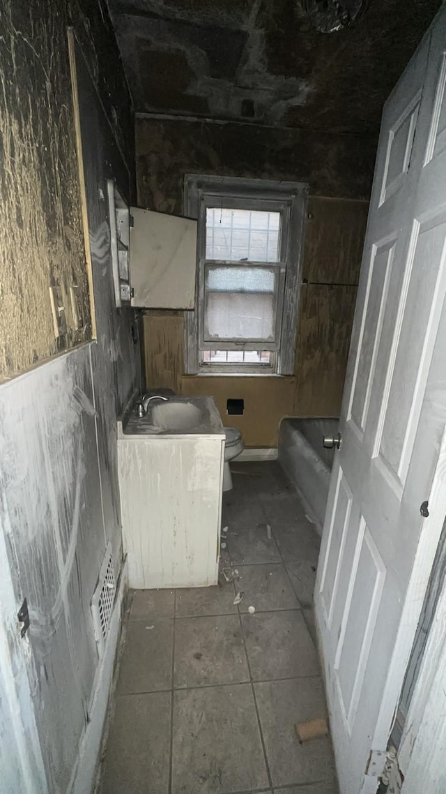 bathroom featuring tile patterned flooring, vanity, toilet, and a tub