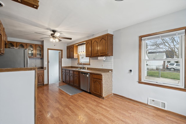 kitchen featuring decorative backsplash, stainless steel appliances, ceiling fan, sink, and light hardwood / wood-style floors