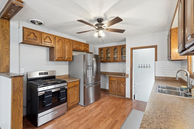 kitchen with ceiling fan, sink, light hardwood / wood-style floors, decorative backsplash, and appliances with stainless steel finishes