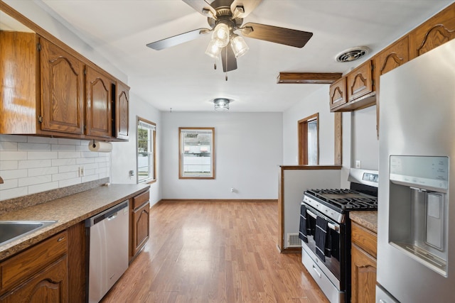 kitchen with ceiling fan, sink, stainless steel appliances, backsplash, and light hardwood / wood-style floors