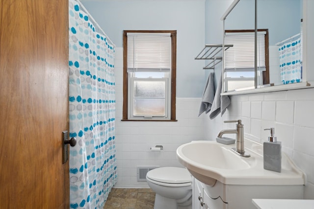 bathroom featuring walk in shower, vanity, toilet, and tile walls