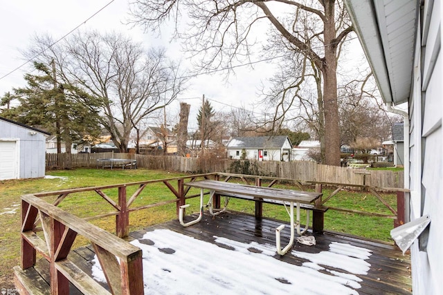 wooden terrace with an outbuilding, a yard, and a trampoline