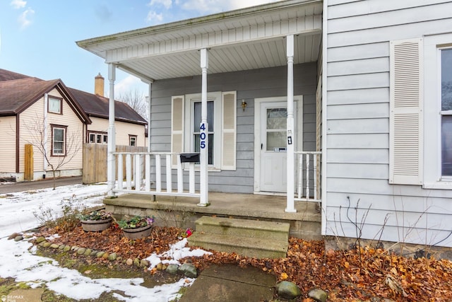 snow covered property entrance with a porch