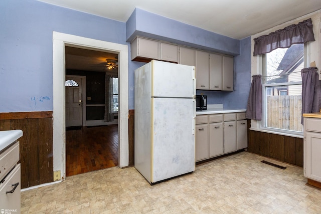 kitchen with ceiling fan, wooden walls, white fridge, and light hardwood / wood-style flooring