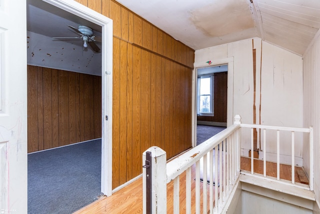 corridor with wood walls and lofted ceiling