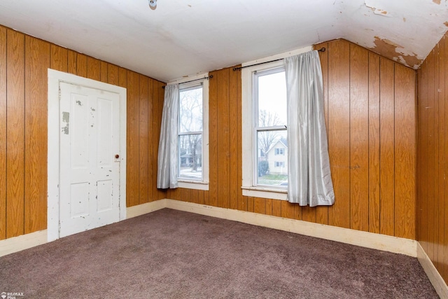 unfurnished room with carpet, lofted ceiling, and wooden walls