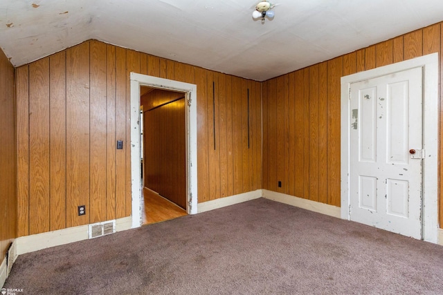 unfurnished room featuring lofted ceiling, light carpet, and wooden walls