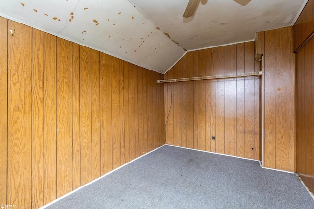 bonus room with ceiling fan, wood walls, carpet floors, and vaulted ceiling