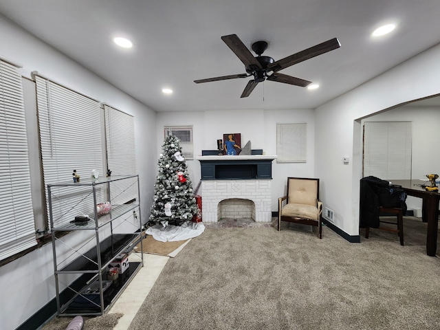 living area with carpet flooring, ceiling fan, and a fireplace